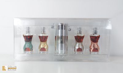 trois flacons de parfum dans une boîte transparente posée sur une table