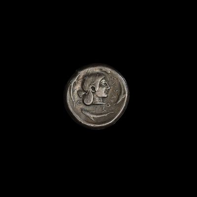 un gros plan d'une pièce de monnaie sur laquelle figure un visage, sur fond noir