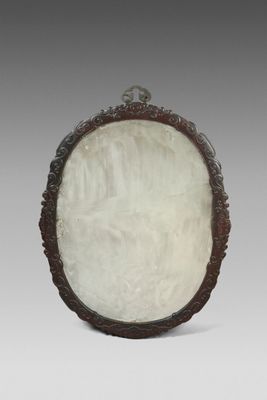 une plaque ovale en jade blanc, ornée de motifs sculptés, posée sur un socle