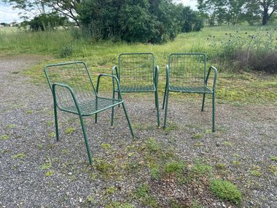 three green chairs sitting in the middle of a gravel road