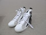 pair of white sneakers with zippers on them sitting on a carpet