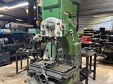 une photo représentant une machine dans un atelier, avec d'autres machines en arrière-plan