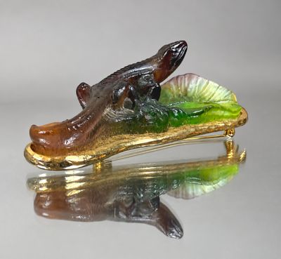 a glass alligator that is sitting on top of a green leaf