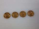 a group of five gold coins sitting on top of a white surface
