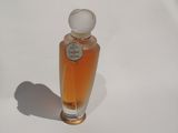 un petit flacon de parfum posé sur une surface blanche