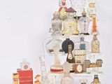 plusieurs flacons de parfum posés sur une étagère, à côté d'un livre
