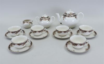 neuf tasses et soucoupes ainsi qu'une théière sur la table