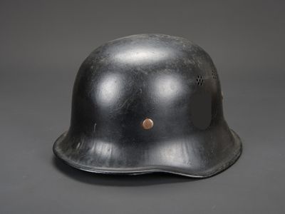 un vieux casque en acier sur fond gris, orné d'un bouton marron