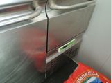 a bag of chips sitting on the floor next to a stainless steel refrigerator