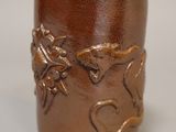 un vase marron orné d'un motif, posé sur une table