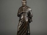a bronze statue of a man in a robe holding a book