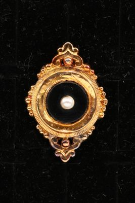 an image of a black and gold broochle with a pearl in it