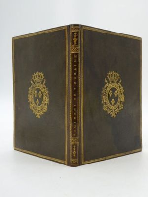 un vieux livre aux tranches dorées et orné d'une couronne sur la couverture