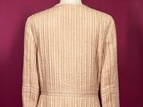 a brown jacket on a mannequin stand against a red wall
