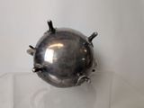 a metal object on a glass shelf on a white surface