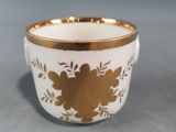 a close up of a white and gold cup on a table