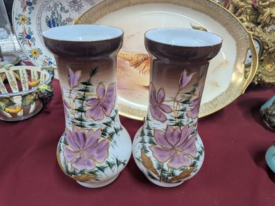 deux vases posés sur une table, avec une assiette à l'arrière-plan