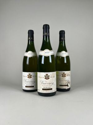 trois bouteilles de vin sont posées sur une table devant un fond gris