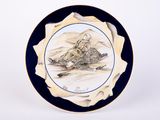 a blue and white plate with a picture of a mountain scene on it