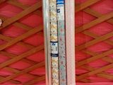 deux rouleaux de papier d'emballage posés sur une nappe rose