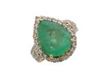 gros plan d'une bague avec une pierre verte entourée de diamants