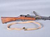 an old machine gun with a sling on a white surface