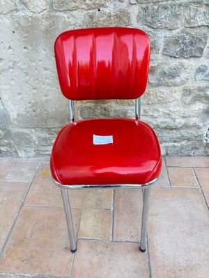 a red chair sitting on a tile floor next to a stone wall