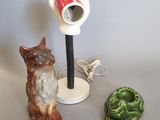 une lampe posée sur une table, à côté d'un chat et d'une figurine de grenouille