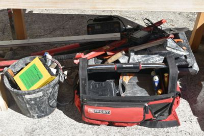 a red tool bag sitting on the ground next to a table