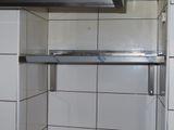 une photo d'une cuisine avec du carrelage blanc et une étagère en inox