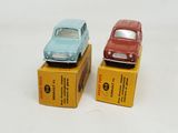 two toy cars sitting on top of boxes on a white surface