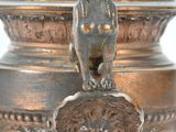 a bronze vase with a lion head on top of it
