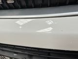 the front bumper of a white car with a sticker on it