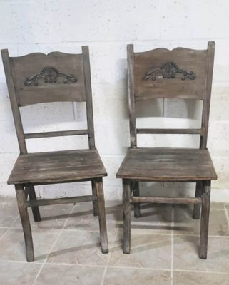 two wooden chairs sitting next to each other on a tile floor