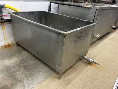 deux cuves en acier inoxydable posées à même le sol dans la cuisine