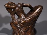 two bronze sculptures of a man and woman sitting on a tree stump