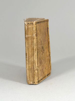 un vieux livre posé sur une table à côté d'un mur blanc