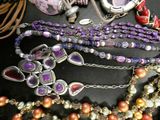 many different necklaces and bracelets that are on a table