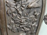 a metal vase with a bird and flower design on it