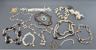 plusieurs colliers et bracelets posés sur une table, à côté d'une paire de ciseaux