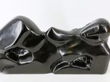 a black sculpture of a cat laying down on a white surface