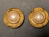 une paire de boucles d'oreilles dorées ornées d'une pierre blanche au centre