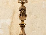 a gold colored candle holder with a face on it
