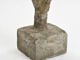concrete sculpture of a bird perched on a rock on a white surface