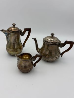 two silver teapots and a silver coffee pot on a white surface