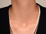 une femme portant un collier de perles et un t-shirt noir