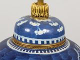 a blue and white vase with a gold top