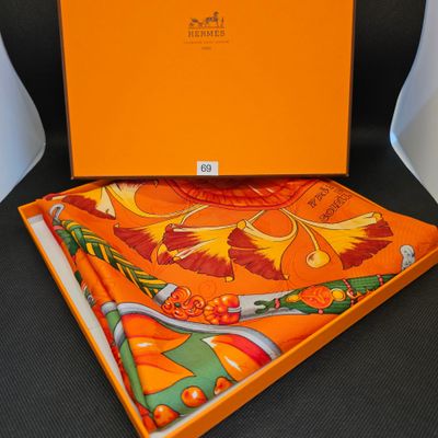 une boîte orange avec une écharpe et un mouchoir assortis, posée sur une chaise noire