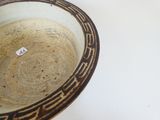 un bol marron et noir posé sur une table blanche