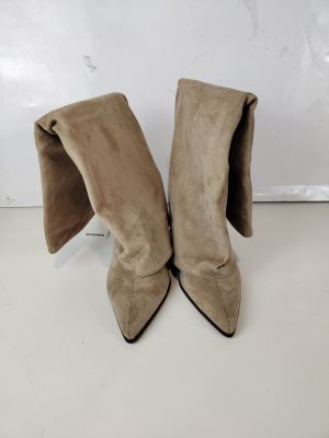une paire de bottes en daim beige posées sur une surface blanche